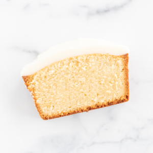 A slice of pound cake on a marble surface.