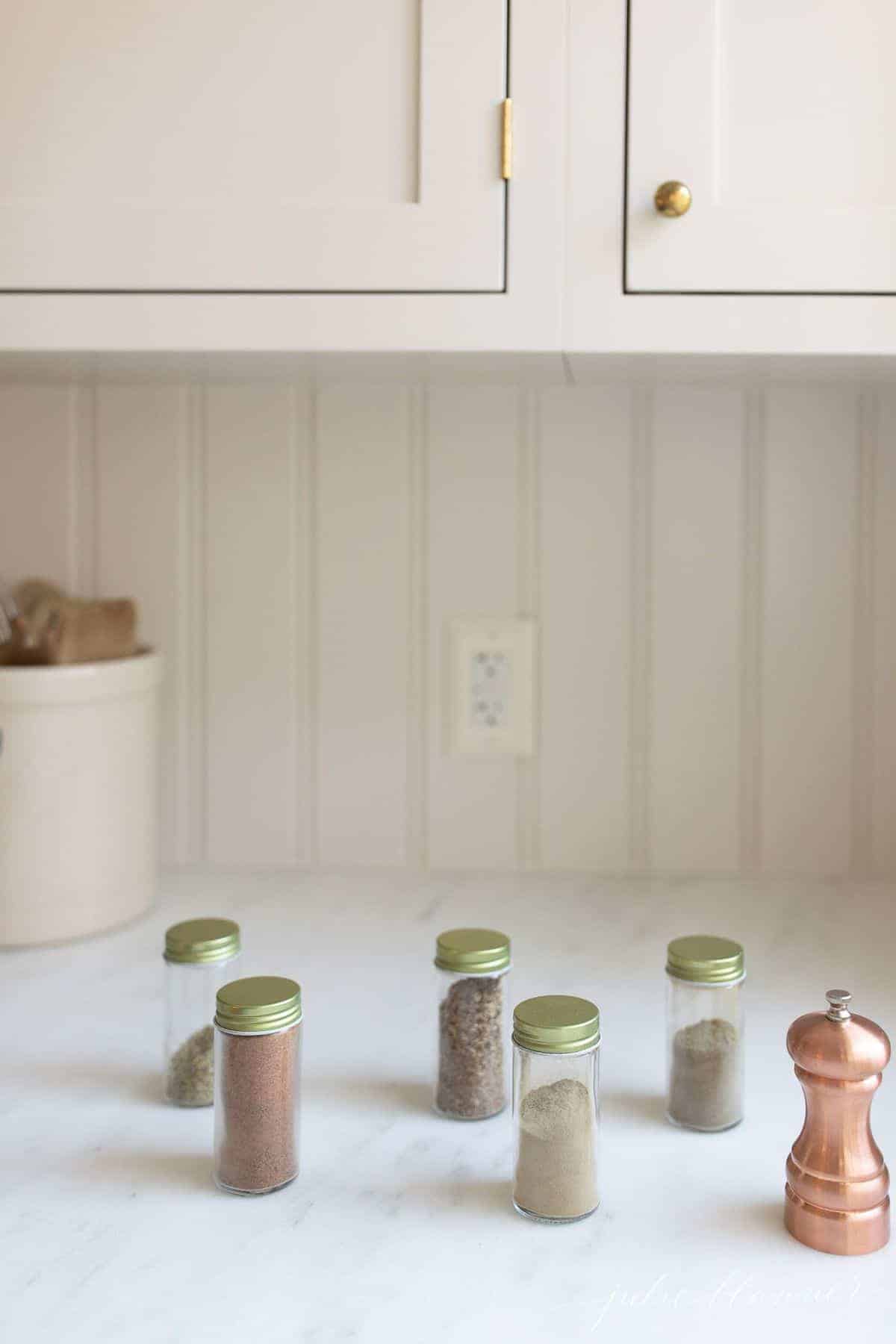 White kitchen with jars of spices in a row for poultry seasoning mix.