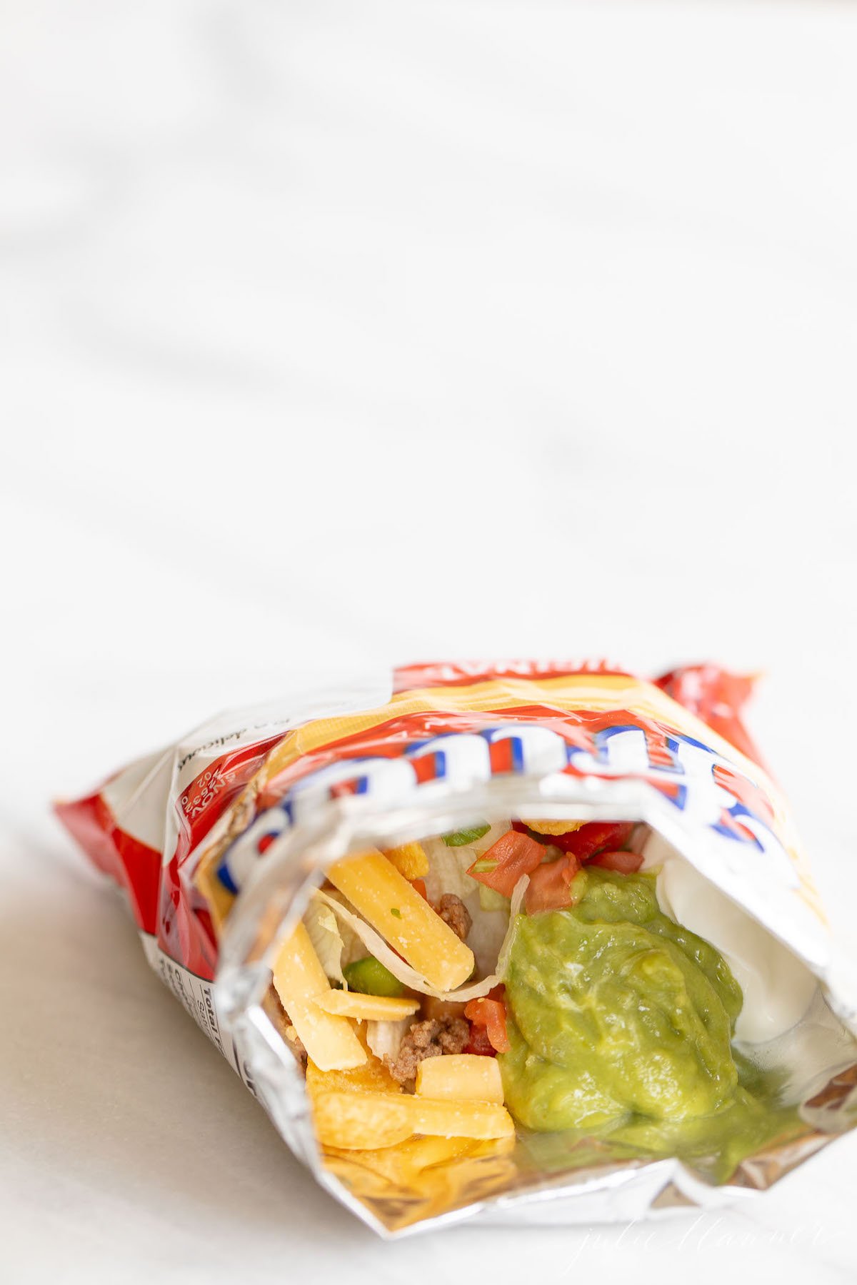 A bag of a walking tacos recipe with sour cream and guacamole.