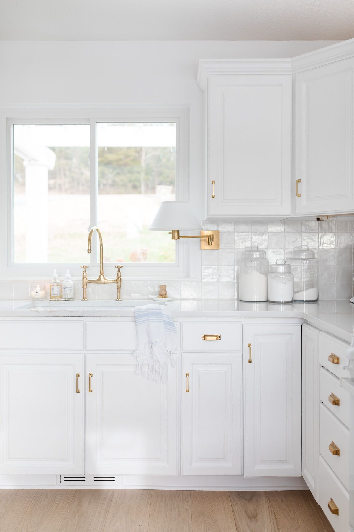 A white kitchen with glass canisters of baking supplies on the countertop