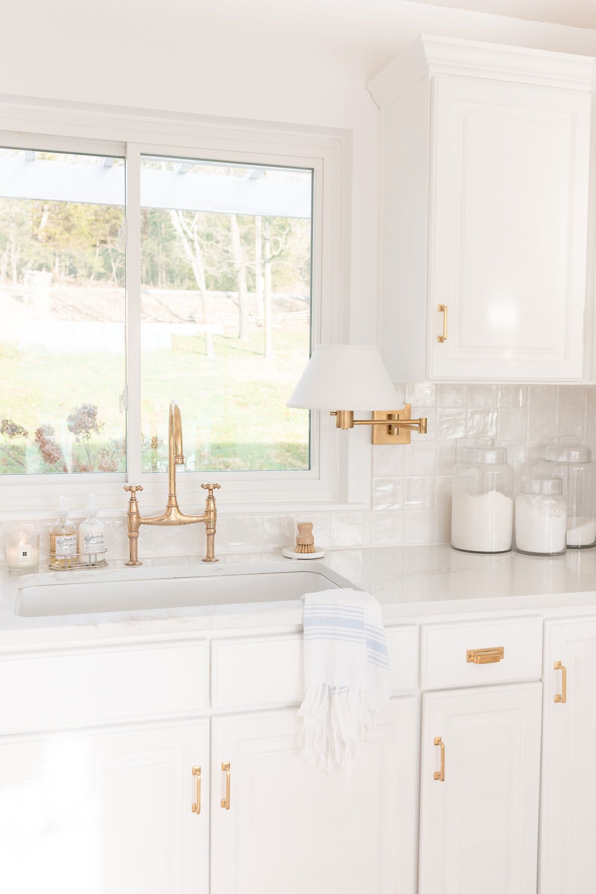 A white kitchen with glass canisters of baking supplies on the countertop