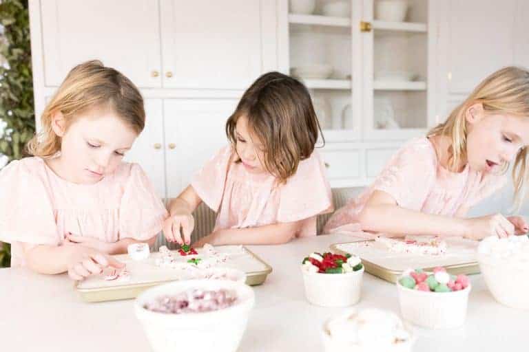 Three little girls wearing pink, decorating a cookie for a baking gift idea at christmas