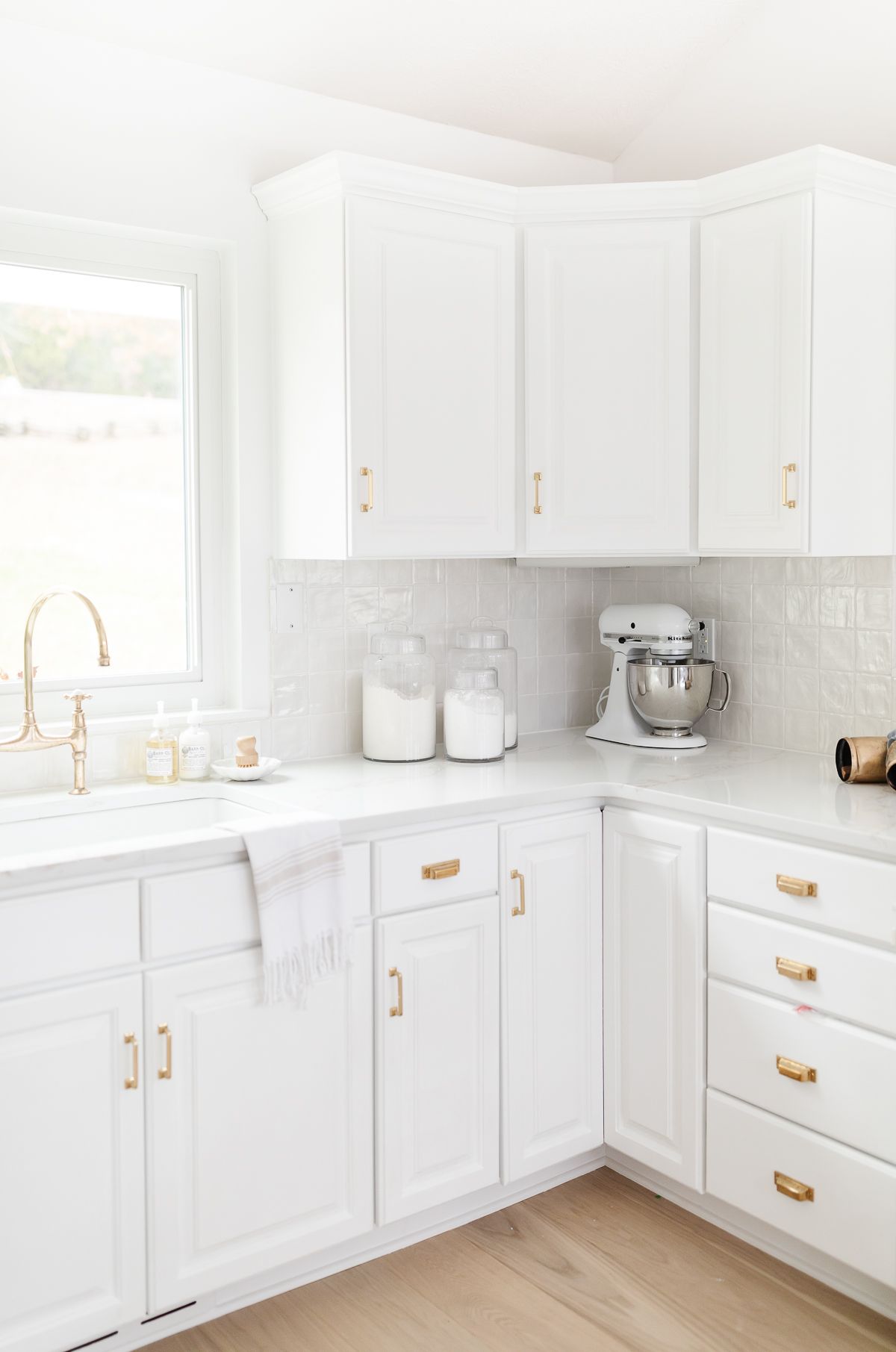 A white kitchen with glass canisters of baking supplies on the countertop