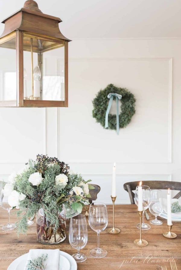 A christmas table setting with a lantern and greenery.