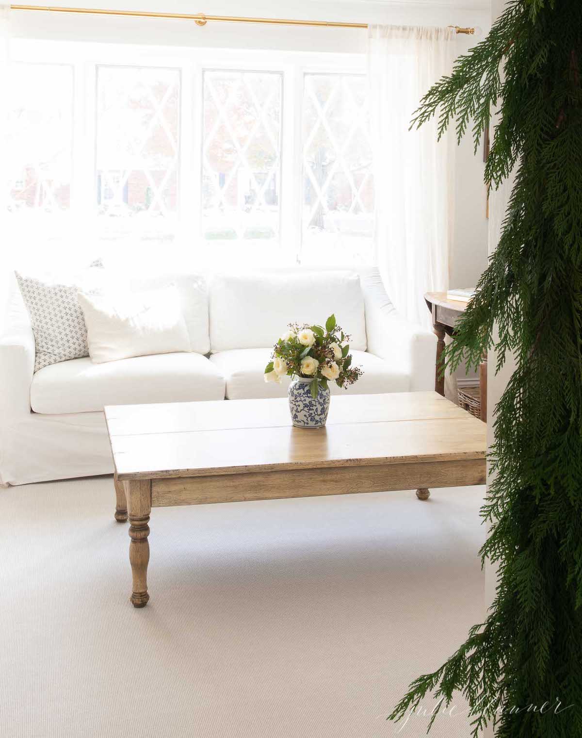 A white living room with a christmas tree in the window.