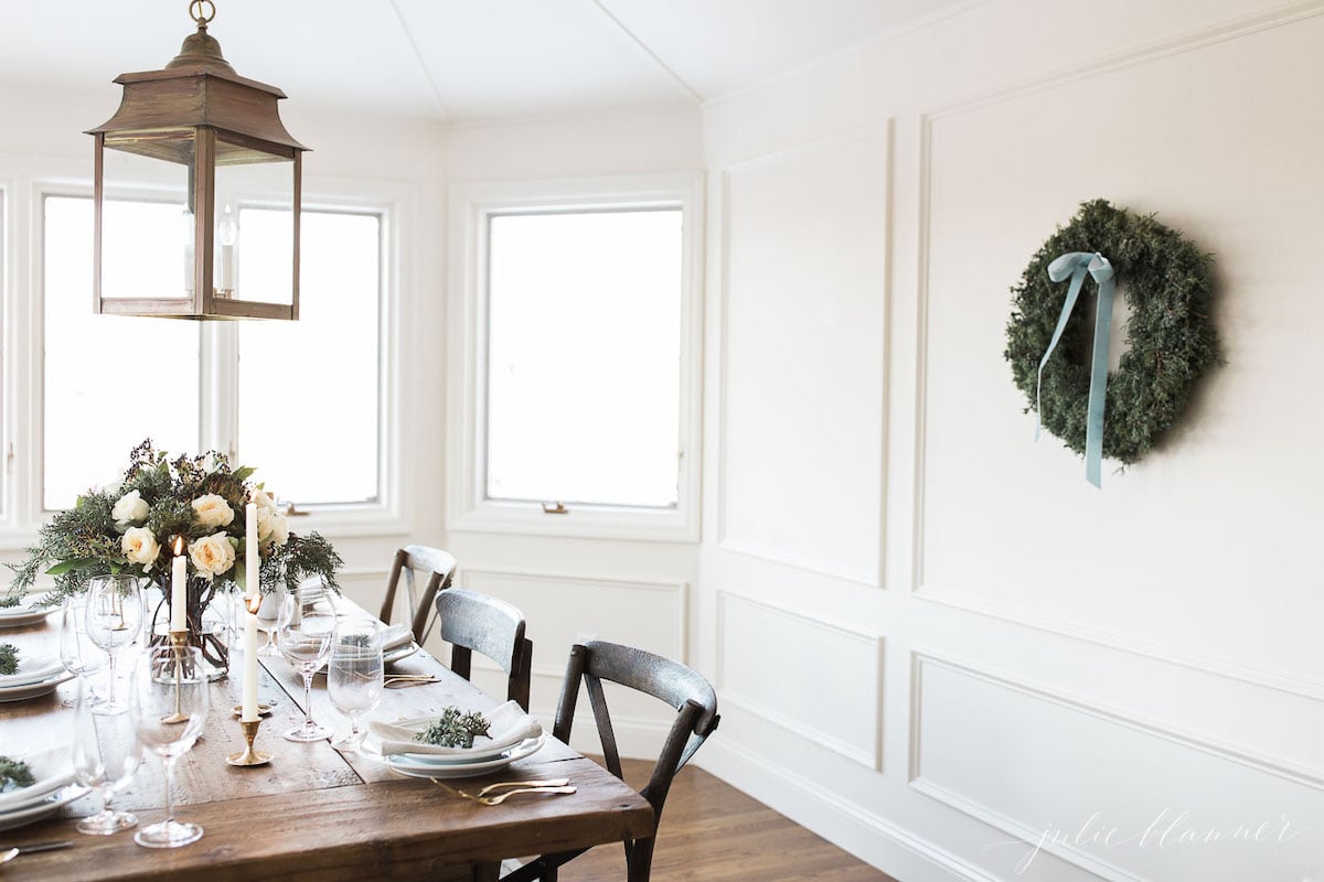A dining room with a table and chairs and a wreath on the wall.