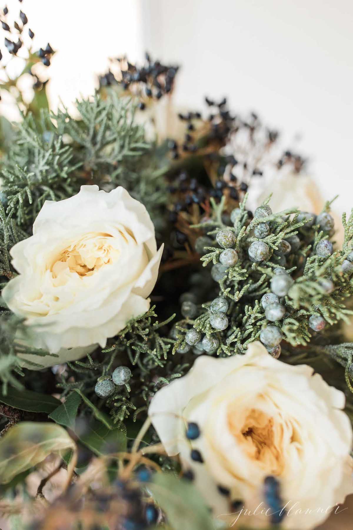 A bouquet of white roses and berries on a table.