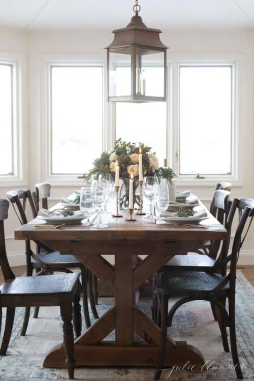 Dining room with wooden table and chairs set with a blue christmas table setting.