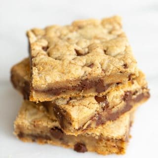 Stack of three cookie bars with chocolate chips and salted caramel.