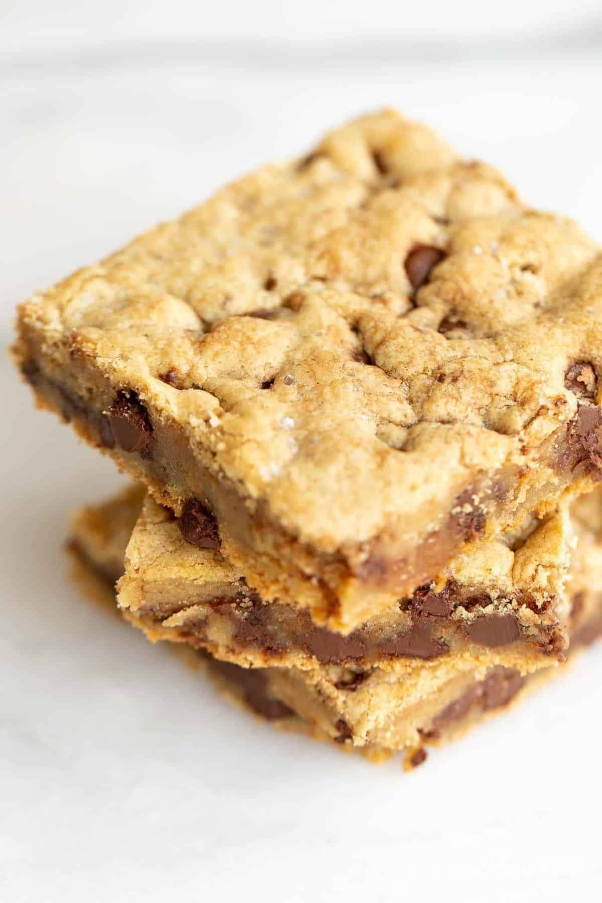 Stack of three cookie bars with chocolate chips and salted caramel.