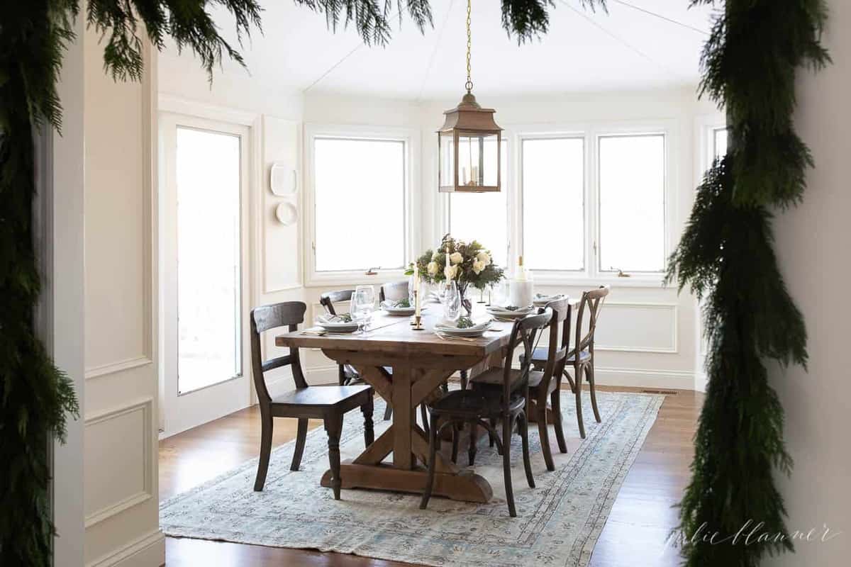 christmas table setting in a breakfast nook draped in cedar garland