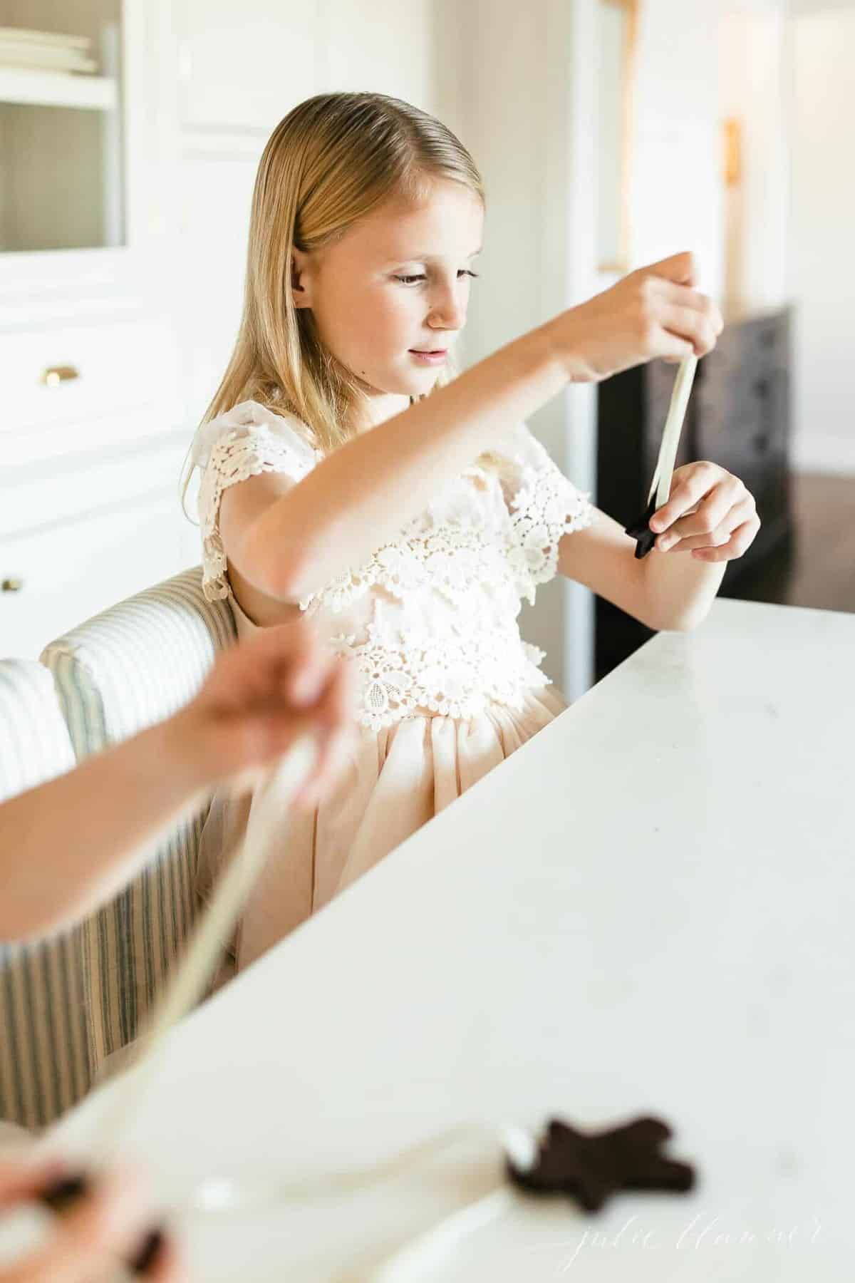 little girl threading ribbon through a cinnamon ornament.