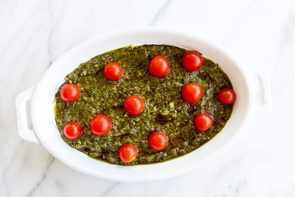 A white bowl filled with pesto and tomatoes, creating an easy appetizer dip.