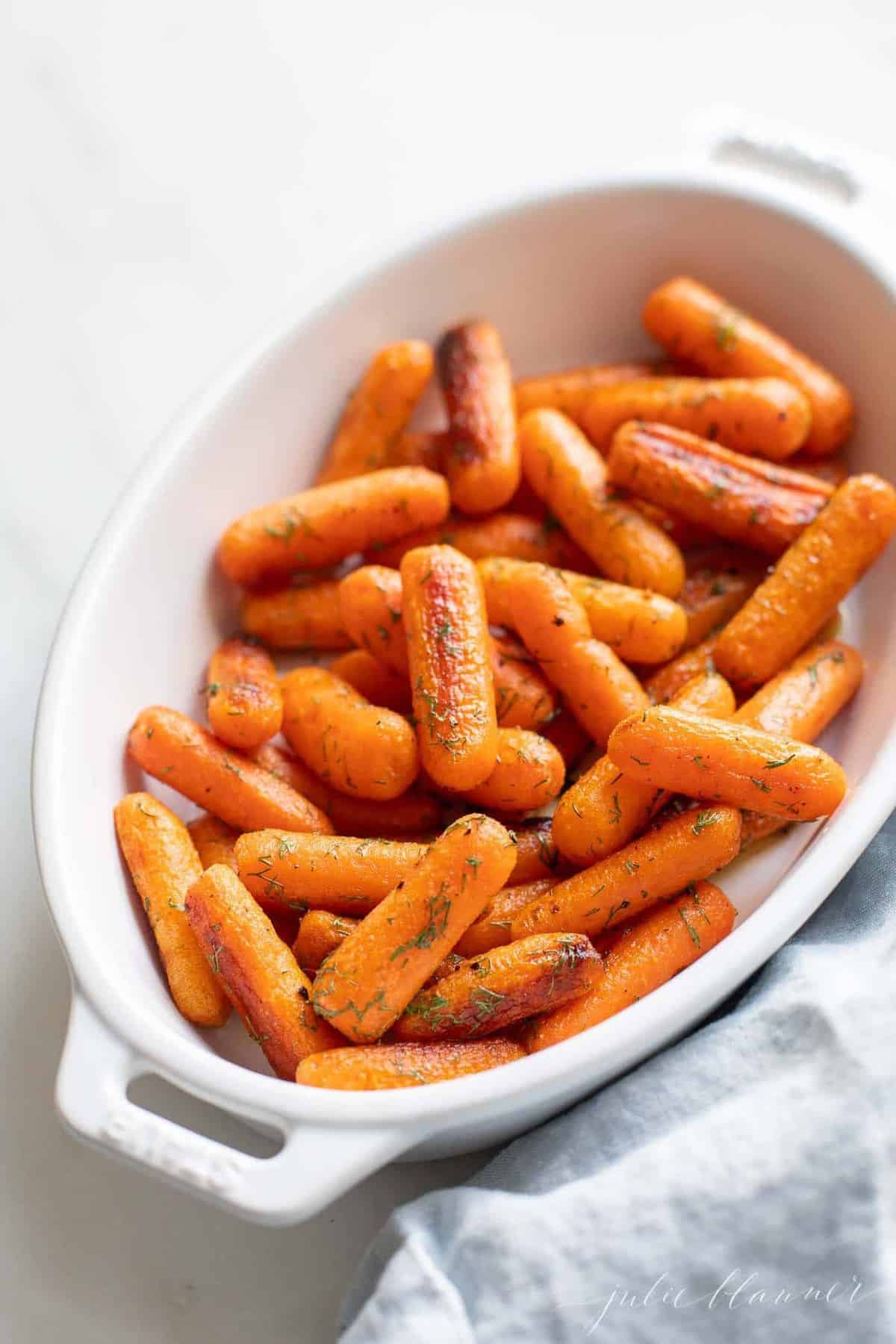 White oval serving platter with roasted dill carrots.