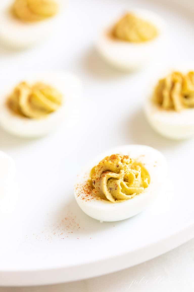 An easy healthy Thanksgiving appetizer, avocado deviled eggs on a white surface.