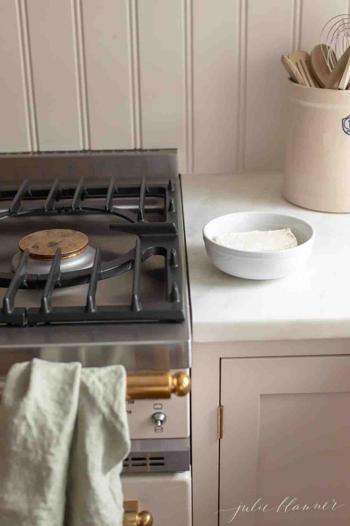 Ivory and brass range with a bowl of cream cheese on the counter beside it.