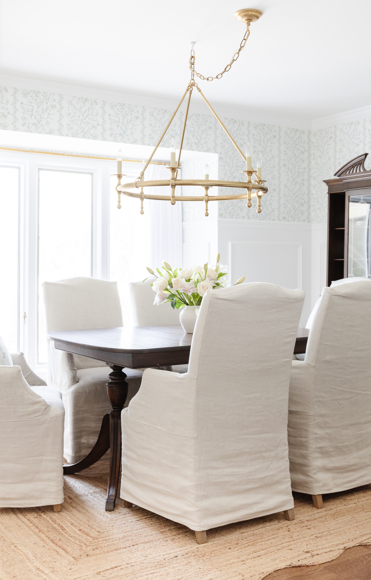 A dining room with white chairs and a chandelier, perfect for Hosting Thanksgiving.