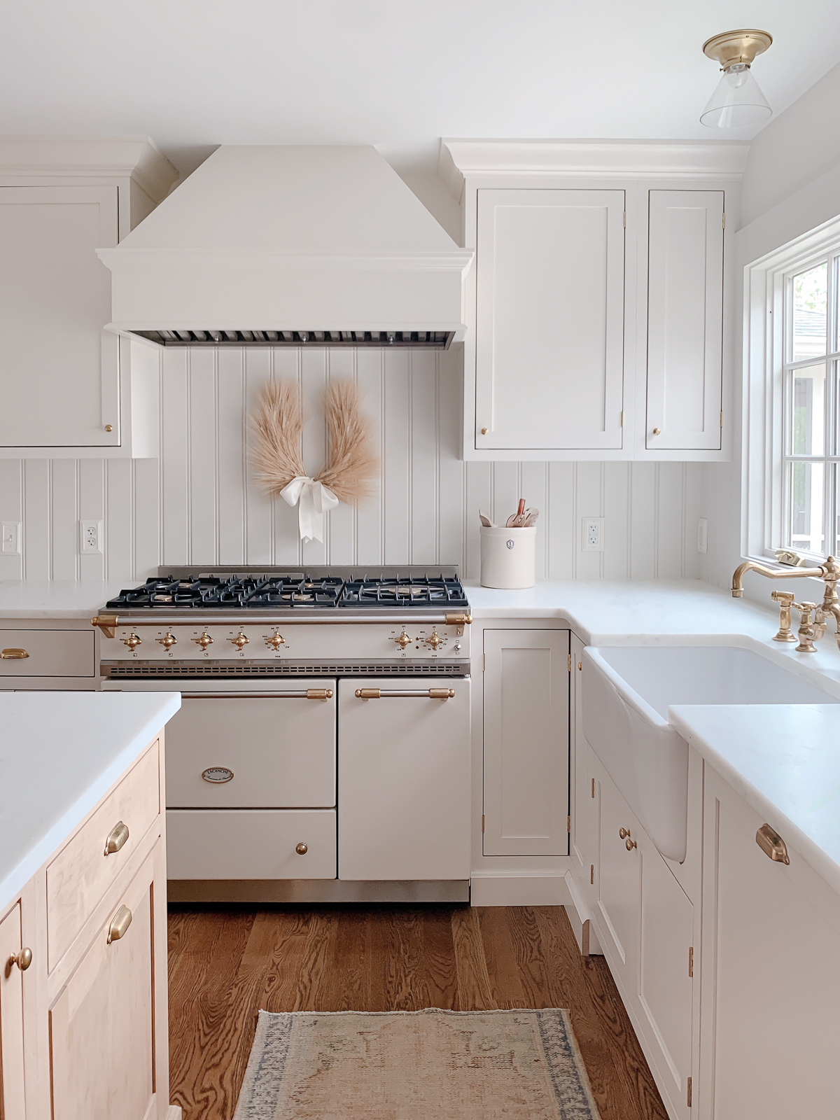 A white kitchen with wood floors and a stove perfect for hosting Thanksgiving.
