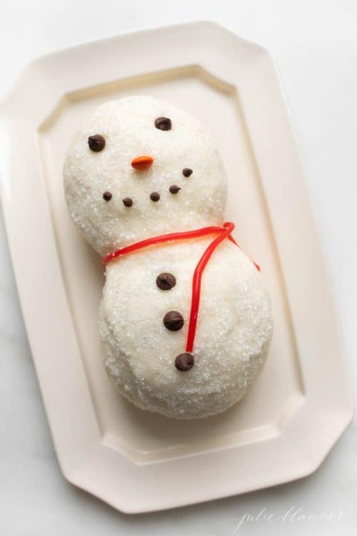 A sugared snowman cheese ball recipe, licorice for scarf on a white platter.