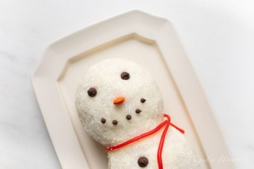 marble surface, white octagonal platter with a funfetti dessert snowman cheese ball.