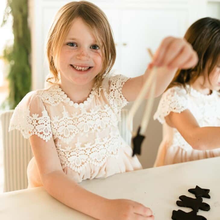 little girl threading ribbon through a cinnamon ornament.