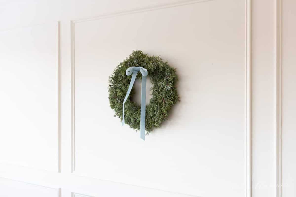 juniper christmas wreath with velvet ribbon hanging on wall