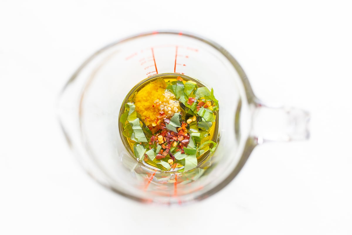A measuring cup filled with a mixture of herbs and spices, perfect for garnishing a goat cheese appetizer.