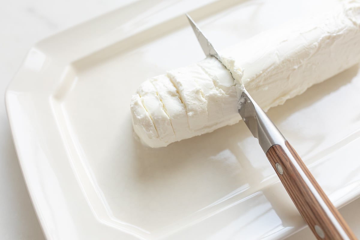 A knife is being used to cut a piece of Chèvre cheese.