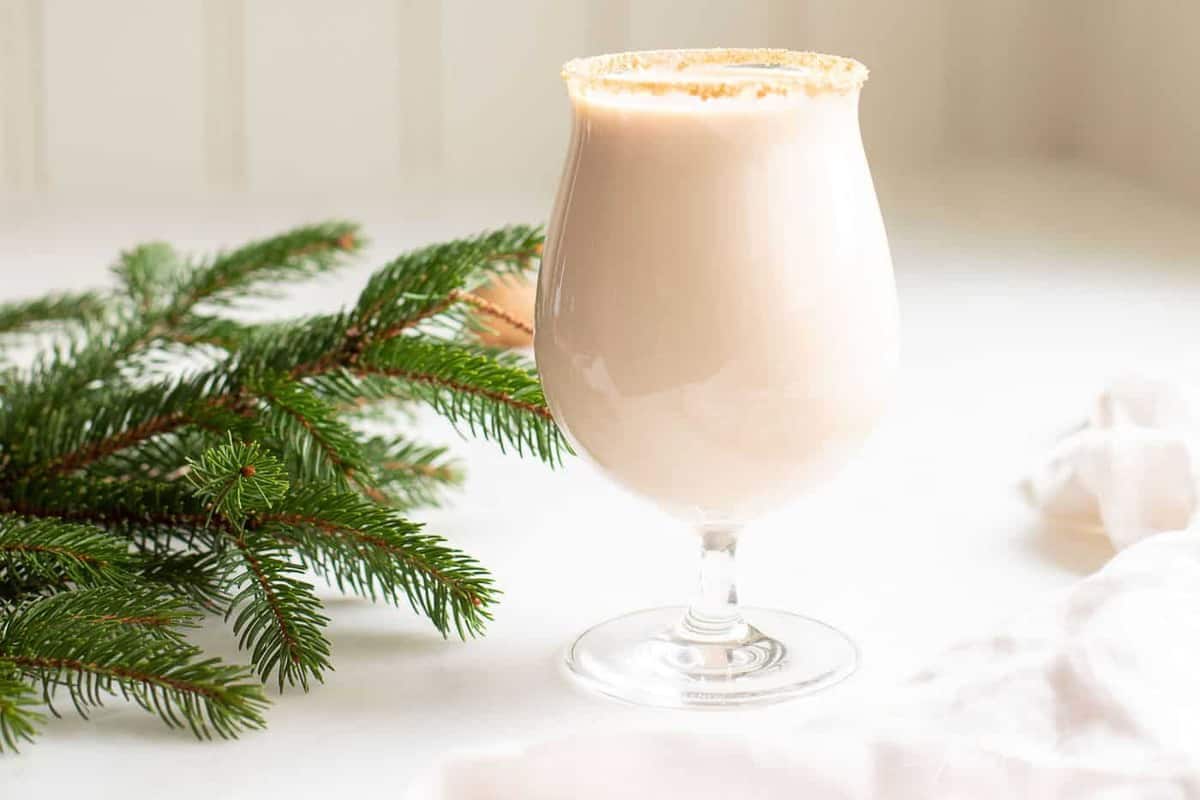 A clear glass with an oatmeal cookie shot, hazelnuts and greenery to the side.