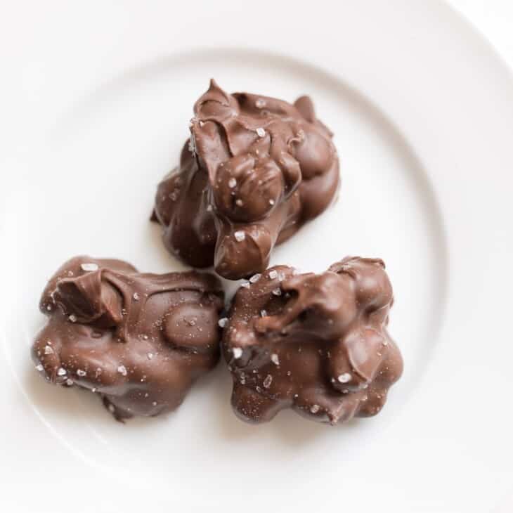 3 peanut clusters topped with sea salt on a white plate
