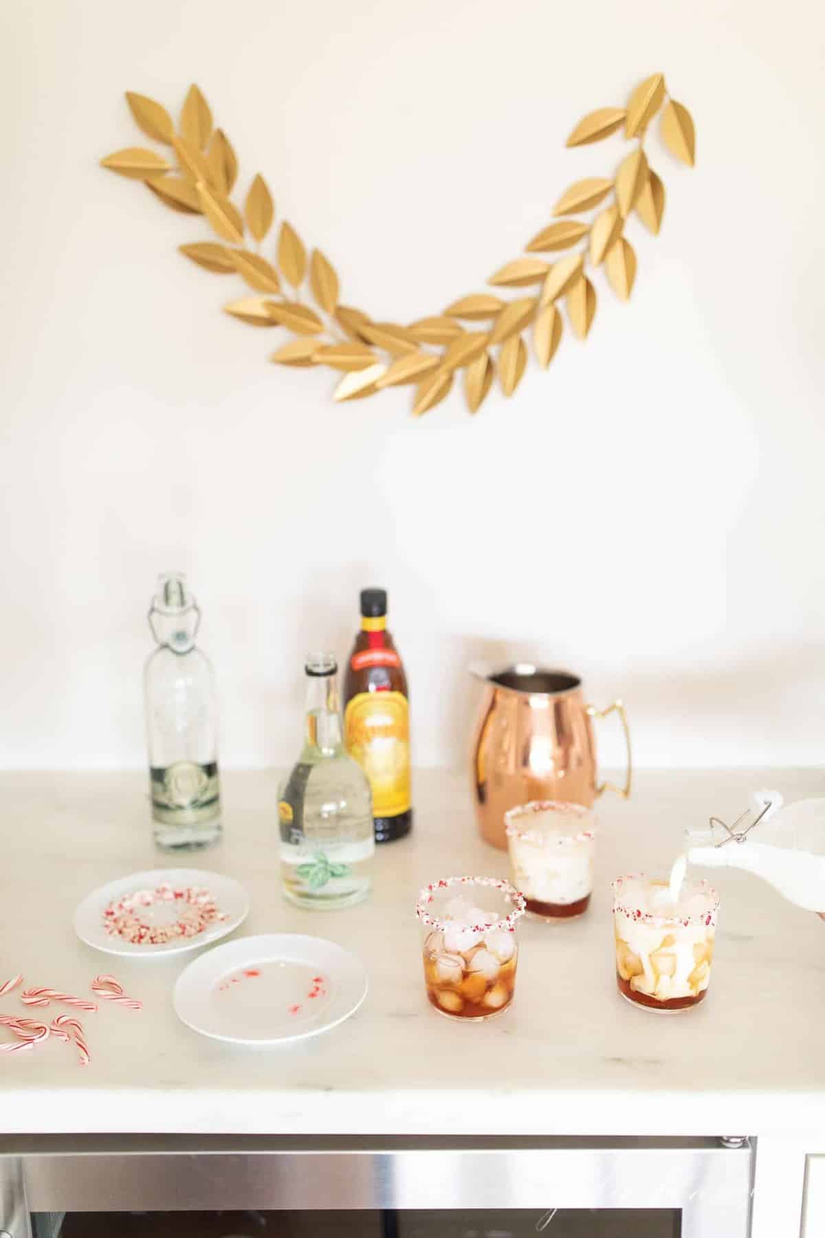 A kitchen bar area set up for peppermint cocktails, milk pouring into peppermint white russian glasses.