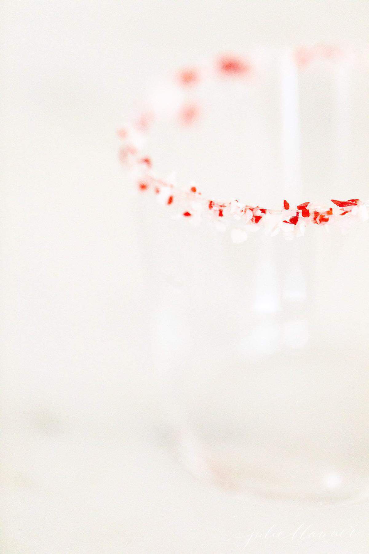 Close up shot of a clear glass rimmed with crushed peppermint.