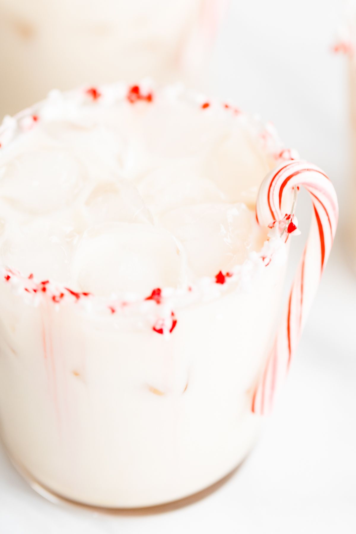 A peppermint white russian cocktail, garnished with a candy cane and crushed peppermint on the rim.