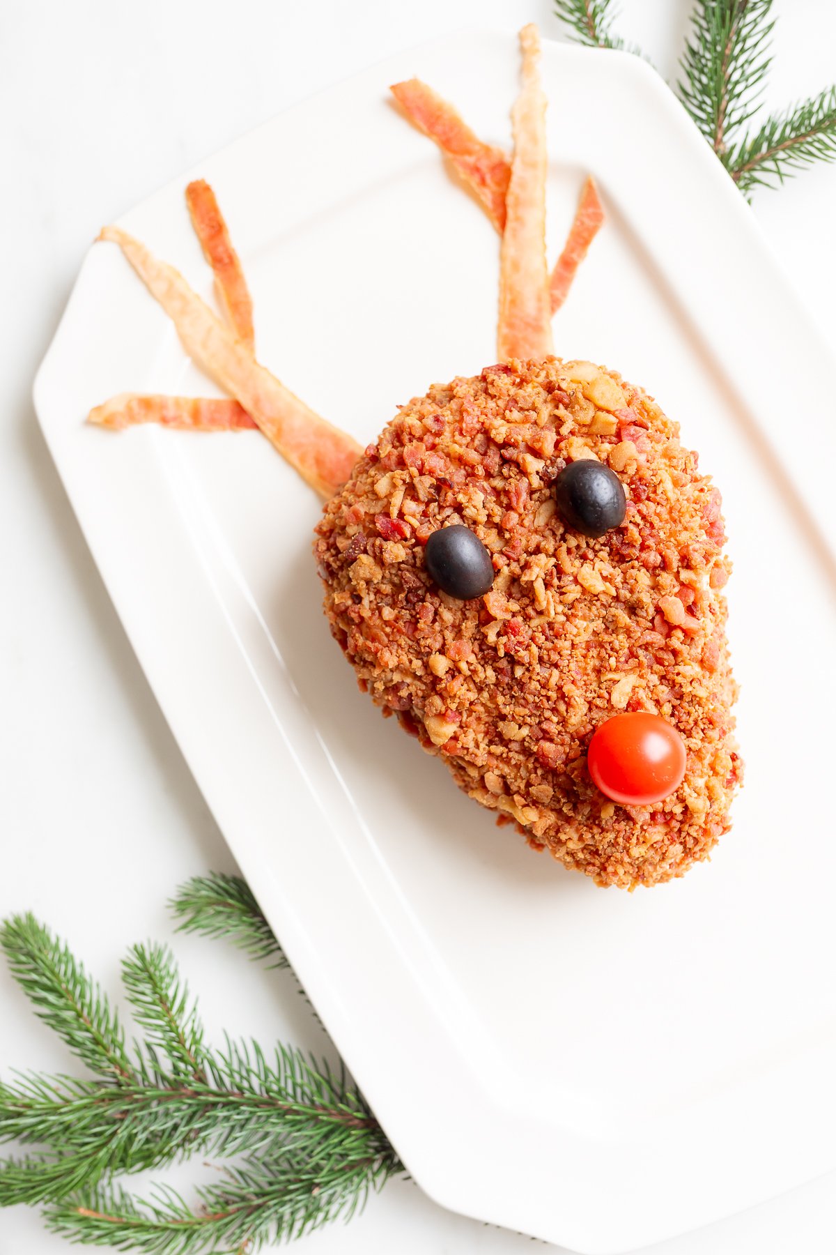 A plate with a reindeer head cheeseball on it.