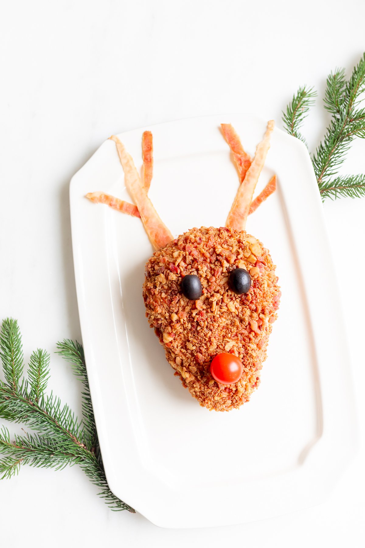 A plate with a reindeer head on it, holding a reindeer cheeseball.