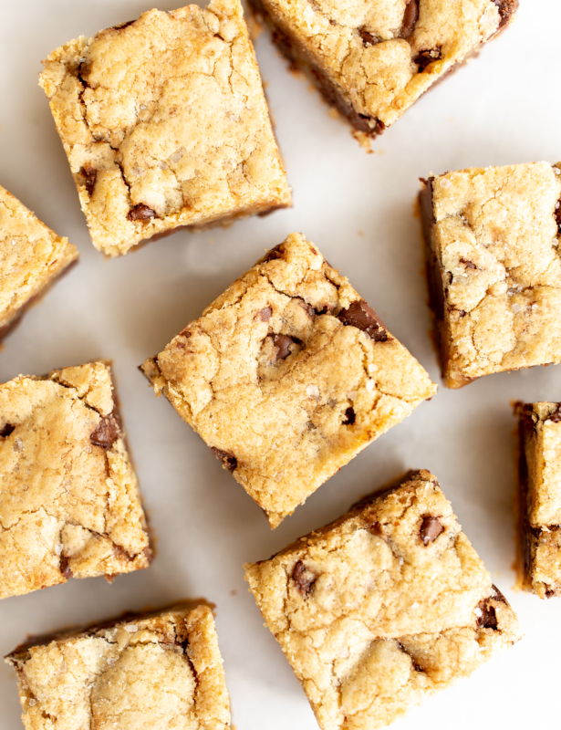 salted caramel chocolate chip cookie bars cut into squares on a white surface.