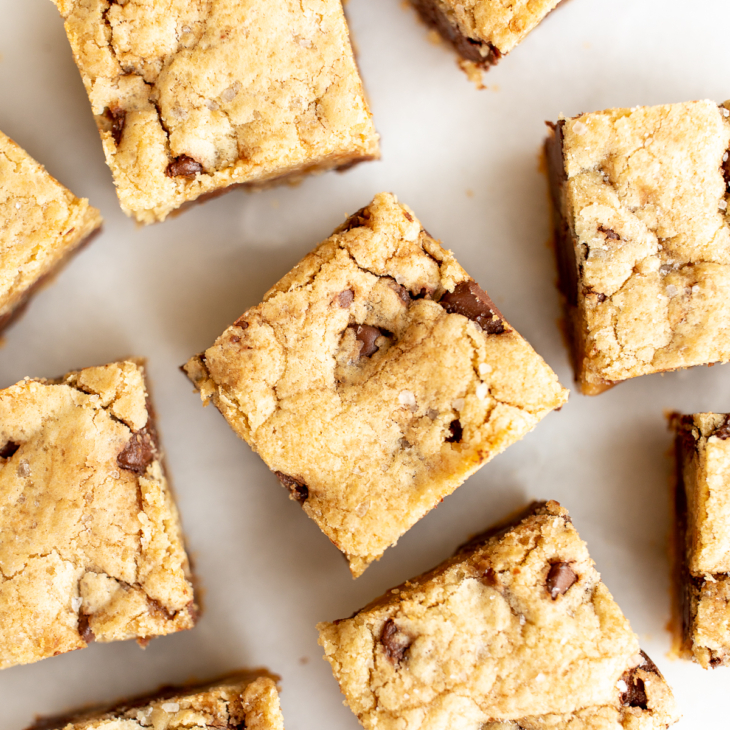 salted caramel chocolate chip cookie bars cut into squares on a white surface.