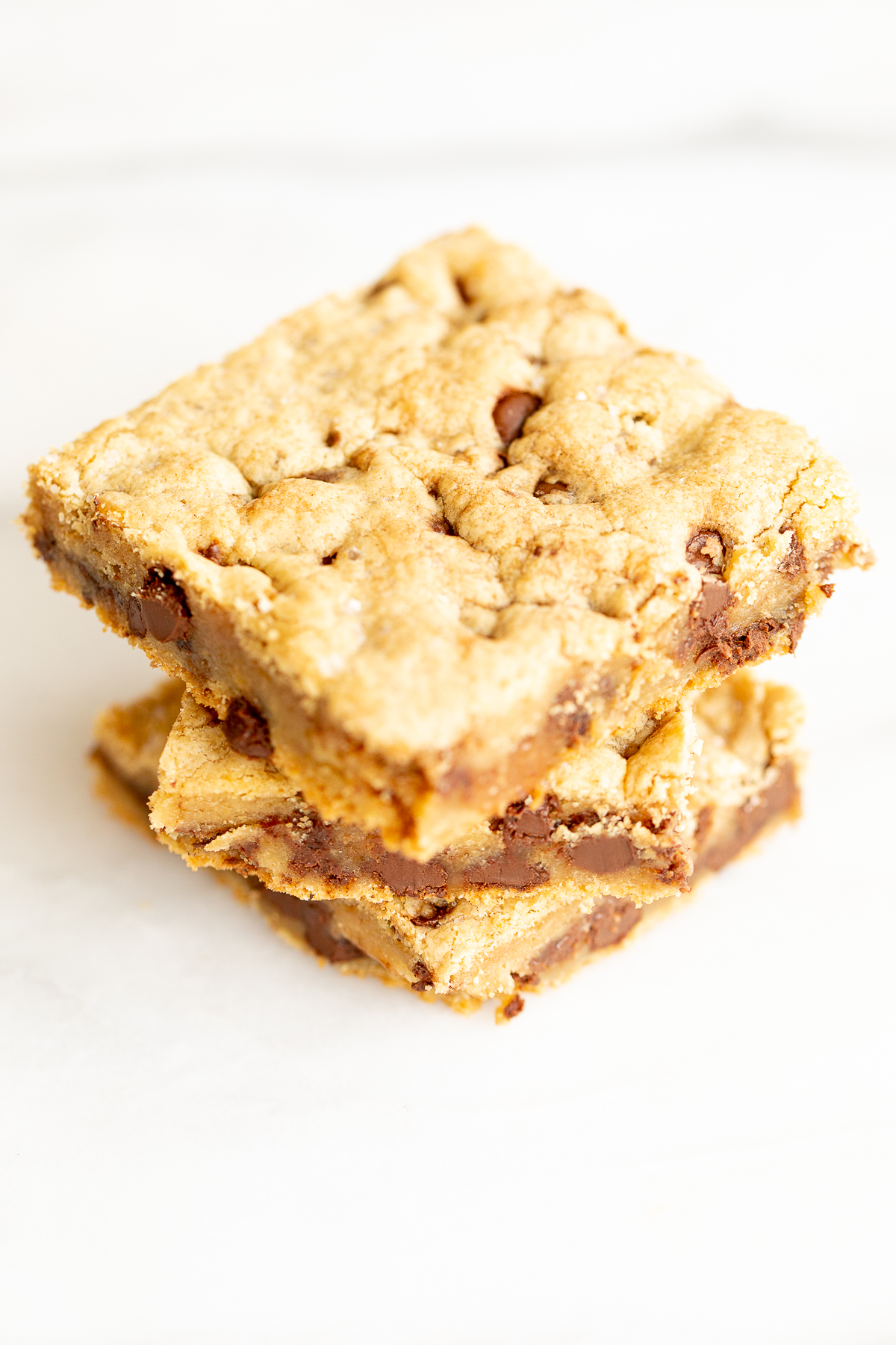 Salted caramel chocolate chip cookie bars cut into squares on a white surface.