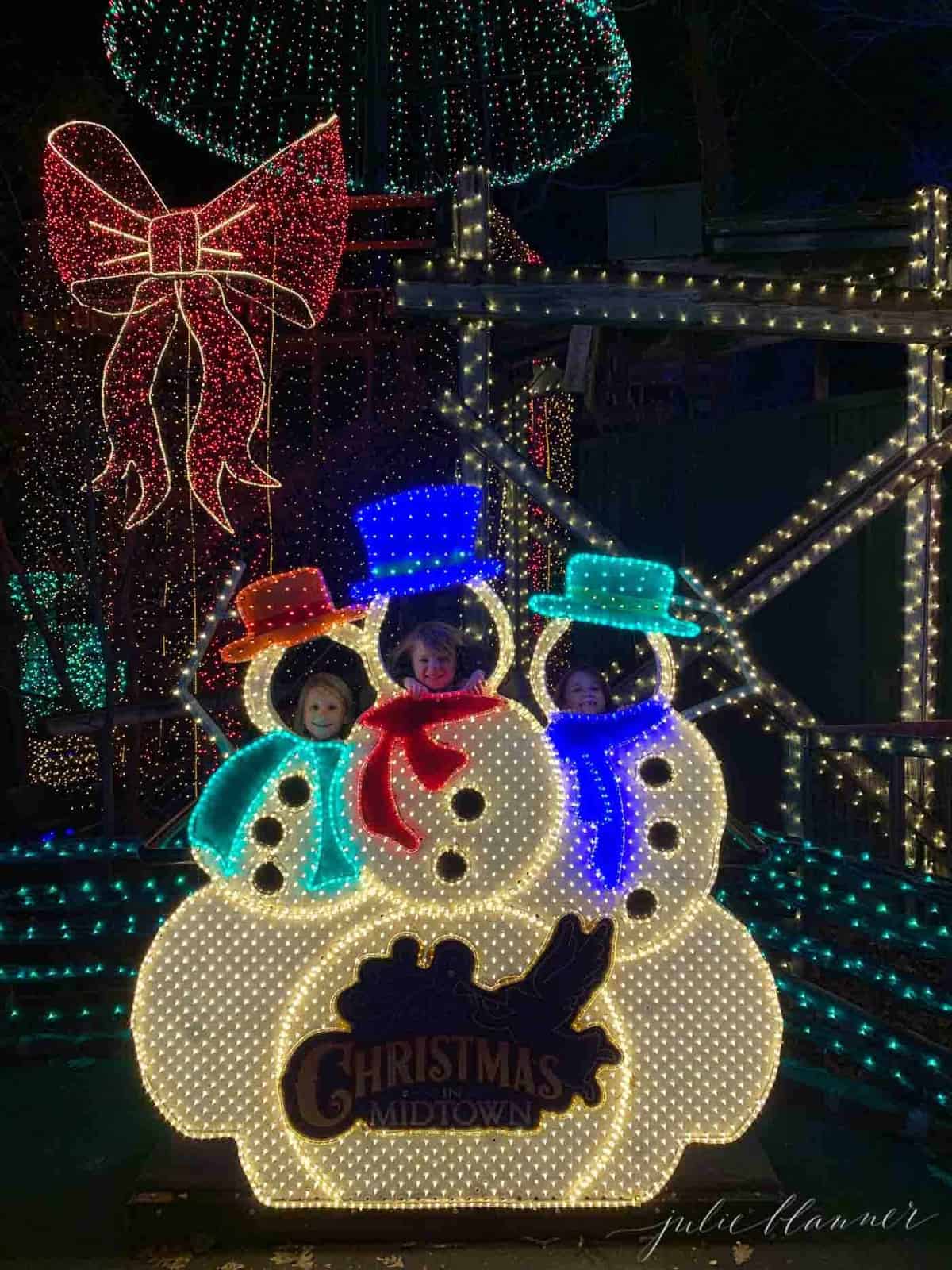 3 girls in snowmen lined with christmas lights