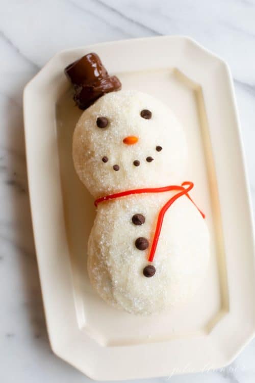 marble surface, white octagonal platter with a funfetti dessert snowman cheeseball.