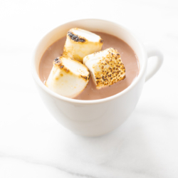 A white mug full of spiked hot chocolate, topped with toasted marshmallows.