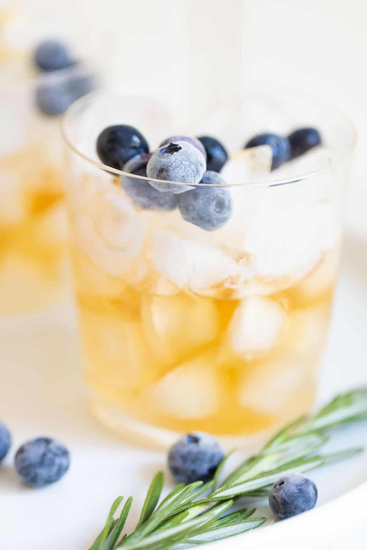 Clear glass with blueberries and ice, whiskey at the bottom.