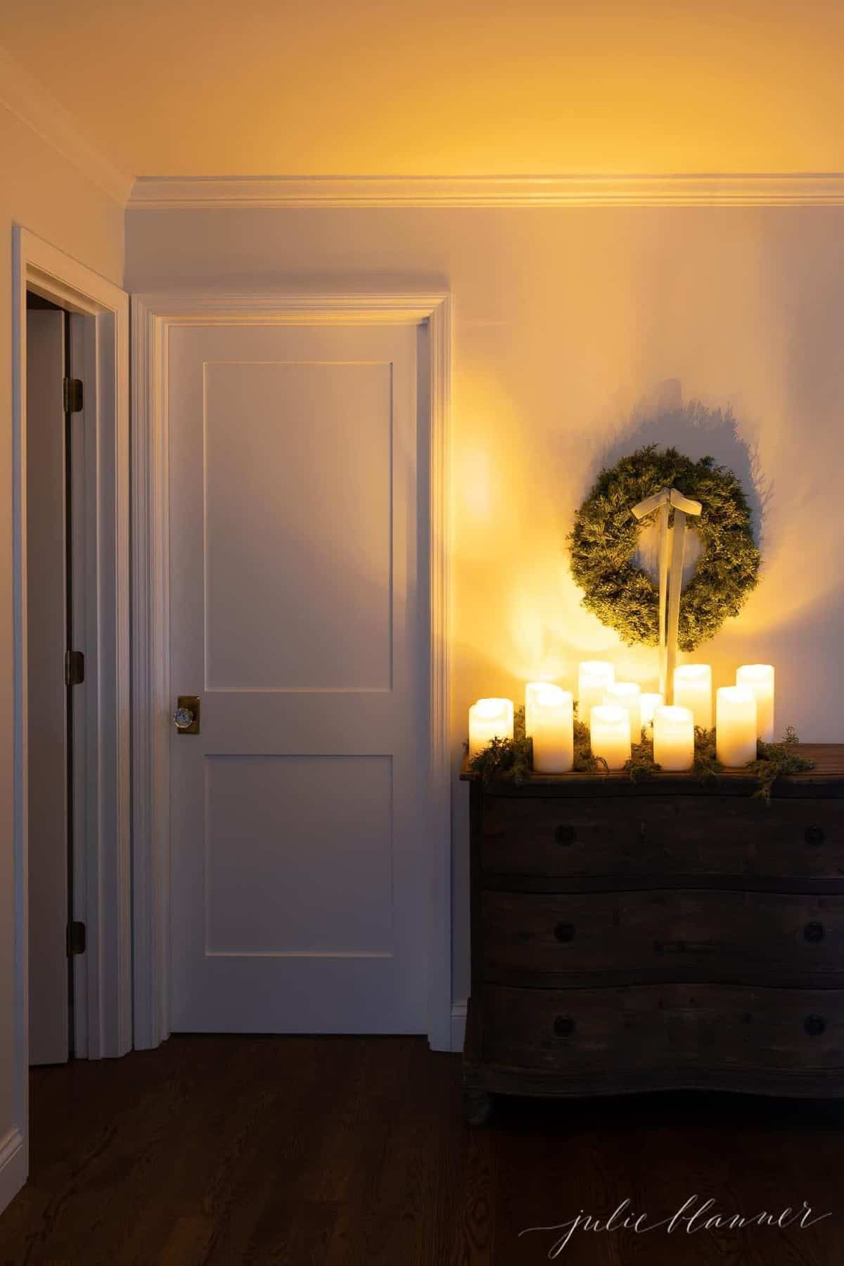 Console table lit with pillar candles, greenery and a Christmas wreath.