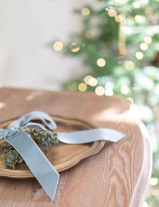 Close up of a wood dresser with a tray of holiday greenery.