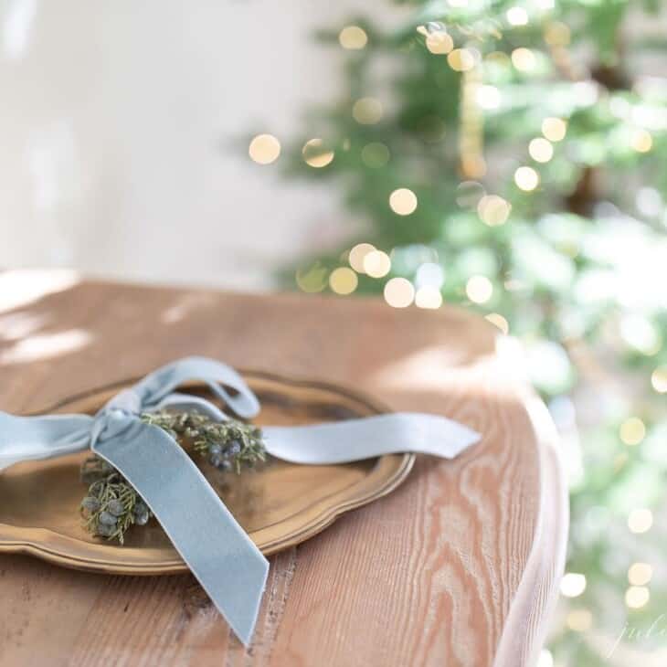 Close up of a wood dresser with a tray of holiday greenery.