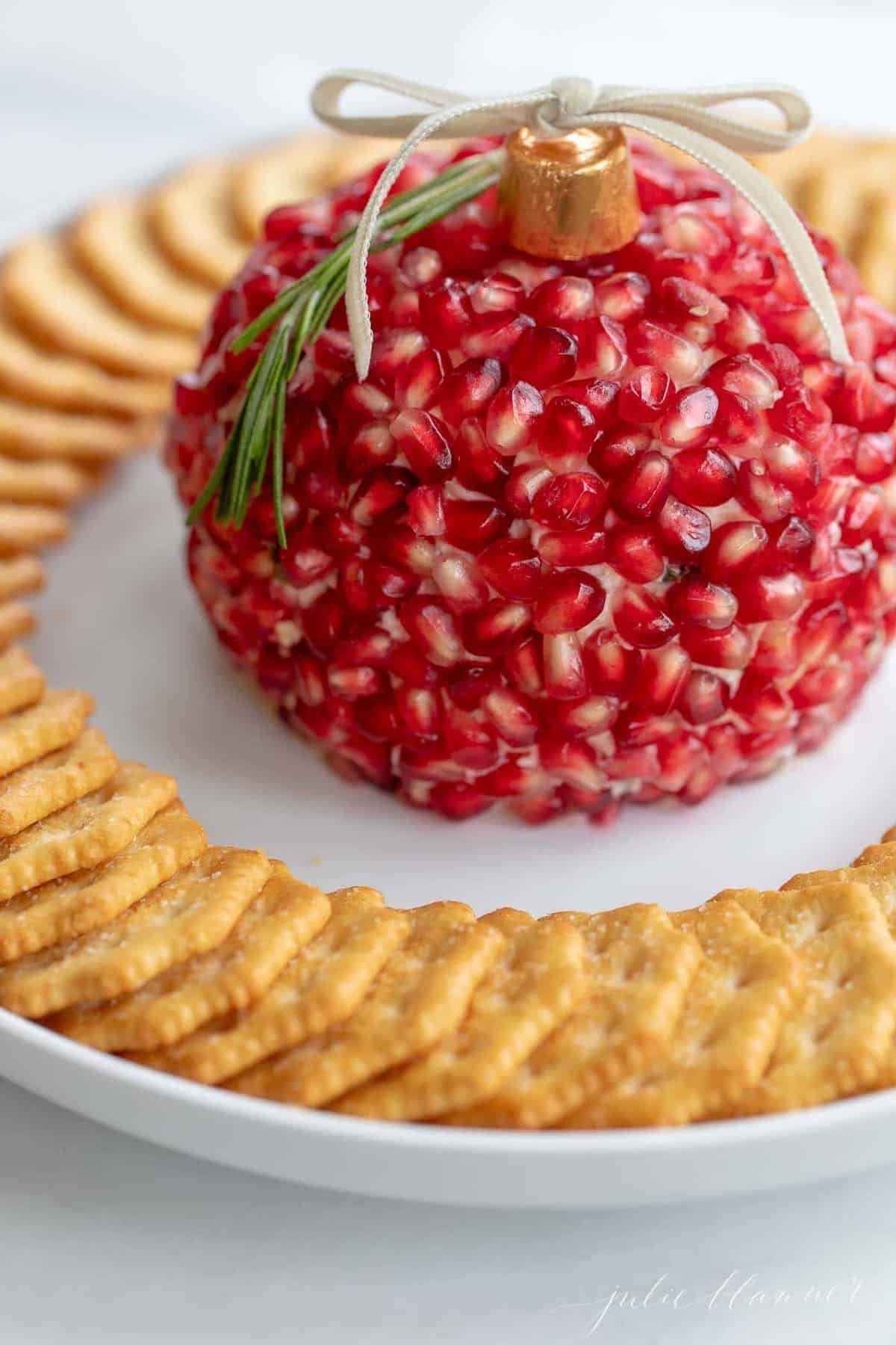 A festive pomegranate cheese ball on a platter with crackers.