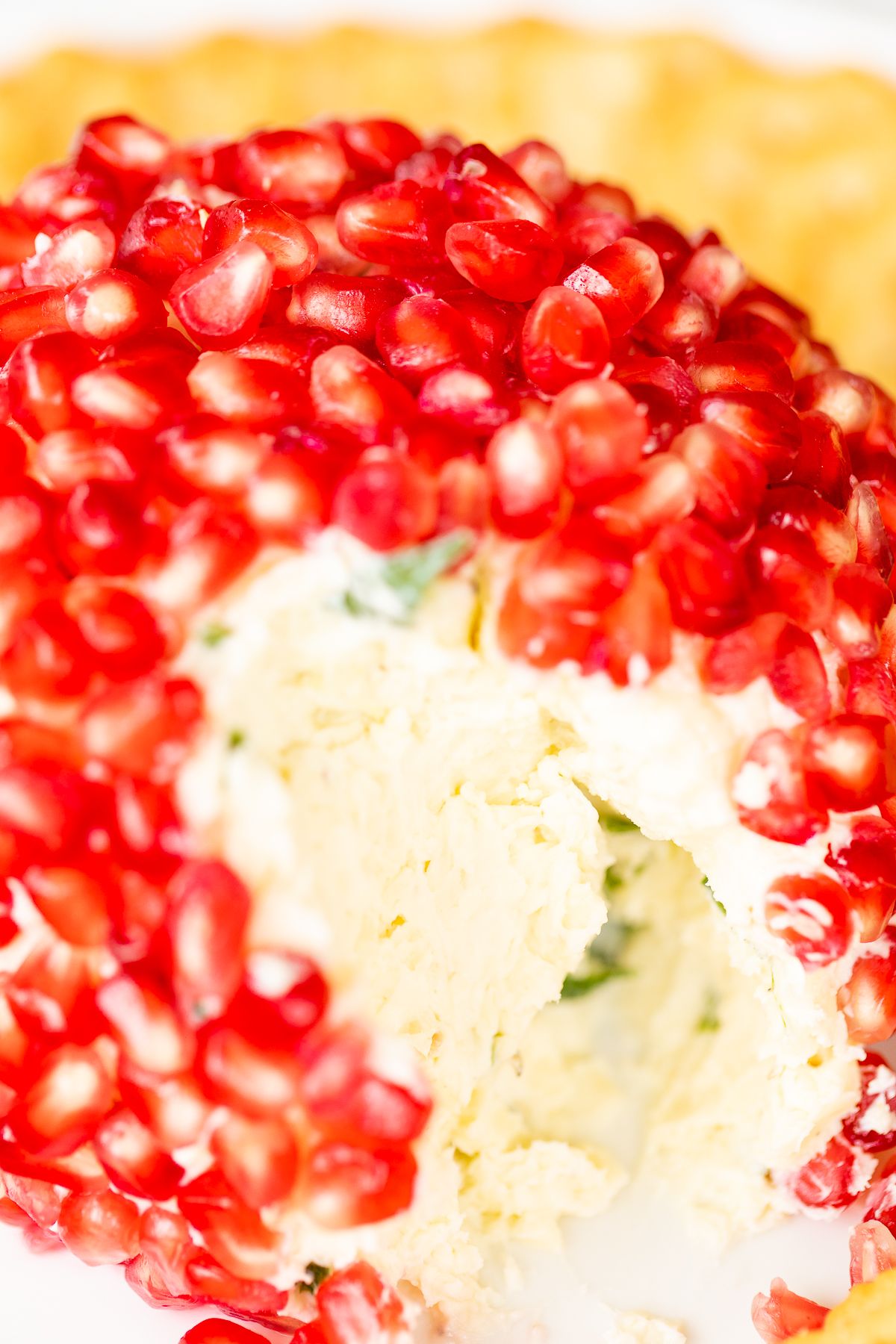 Looking inside a savory pomegranate cheese ball, with crackers in the background
