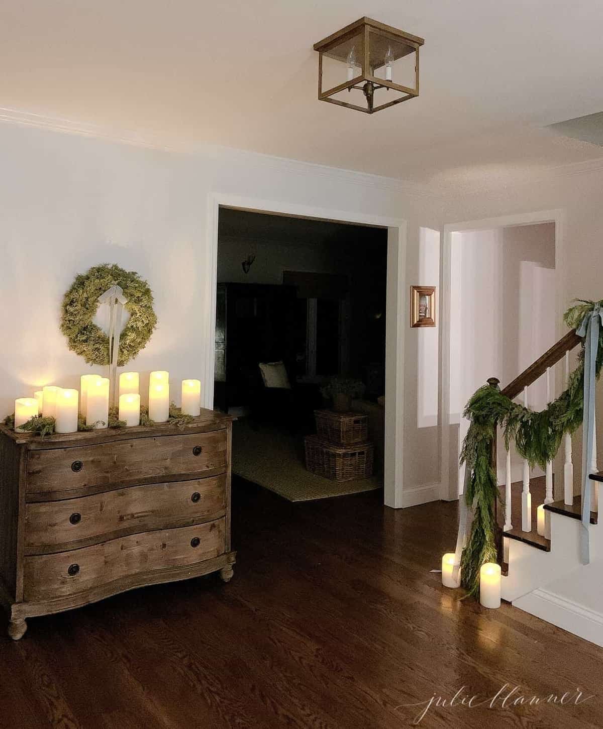 Darkly lit entryway at night, candles and evergreens decorating for Christmas.