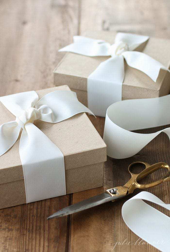 A wooden surface with Kraft boxes wrapped in white ribbon.