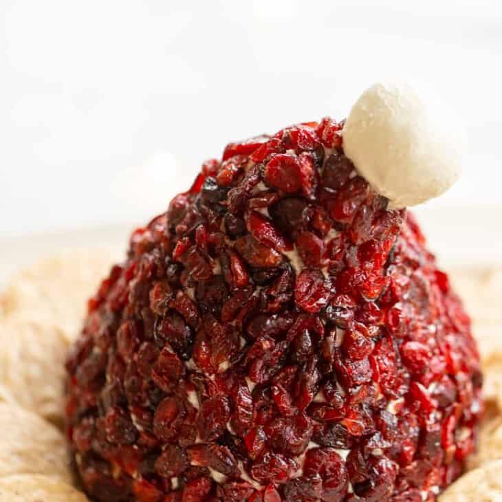 santa hat shape cranberry cheese ball on a platter with crackers
